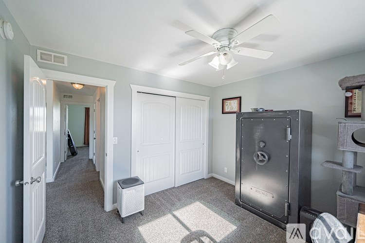 A room with a ceiling fan and a large metal cabinet.