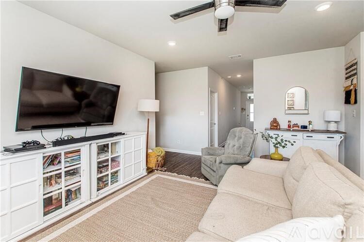 A living room with a flat screen TV on a cabinet and a grey sofa.