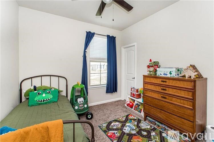 A room with a bed, a dresser, and a window with blue curtains.