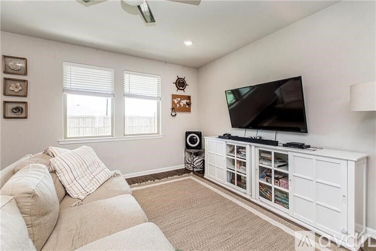 A living room with a television, a sofa, and a fan.