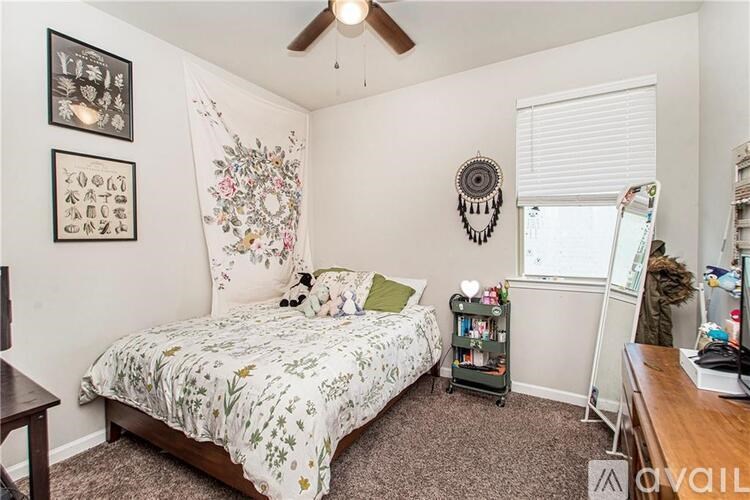 A bedroom with a bed, a ceiling fan, and a wall hanging.
