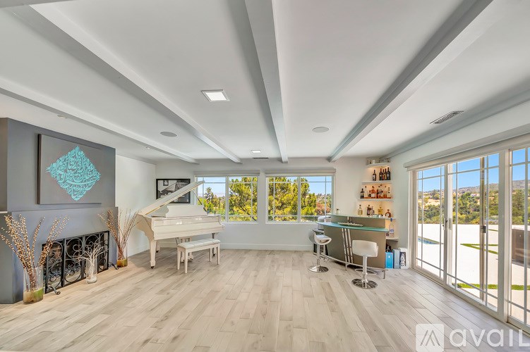 A spacious room with a grand piano and a view of the outdoors through large windows.
