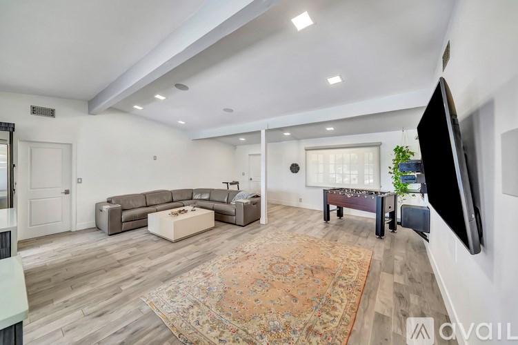 A living room with a grey sofa set and a rug in the middle.