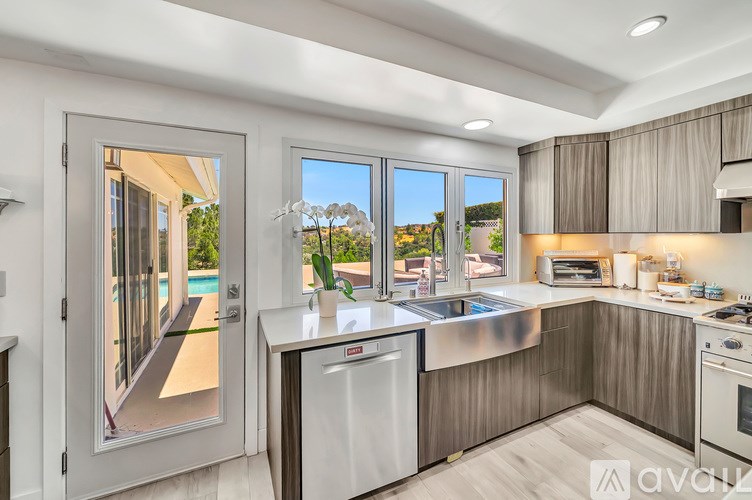 A modern kitchen with a large window overlooking a pool.