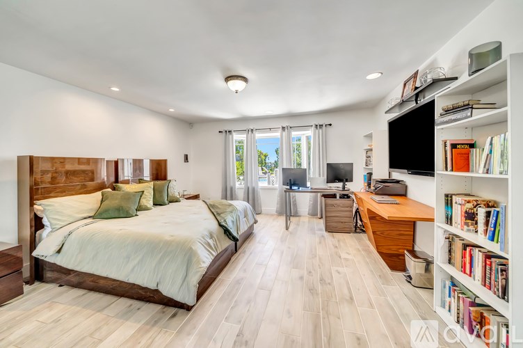 A bedroom with a large bed and a desk with a chair.