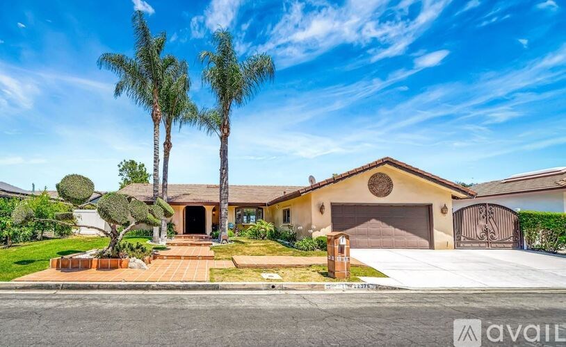 A house with a driveway and palm trees in front.