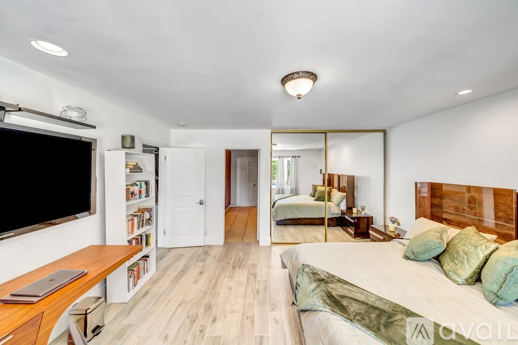 A bedroom with a bed, a television, and a mirror.