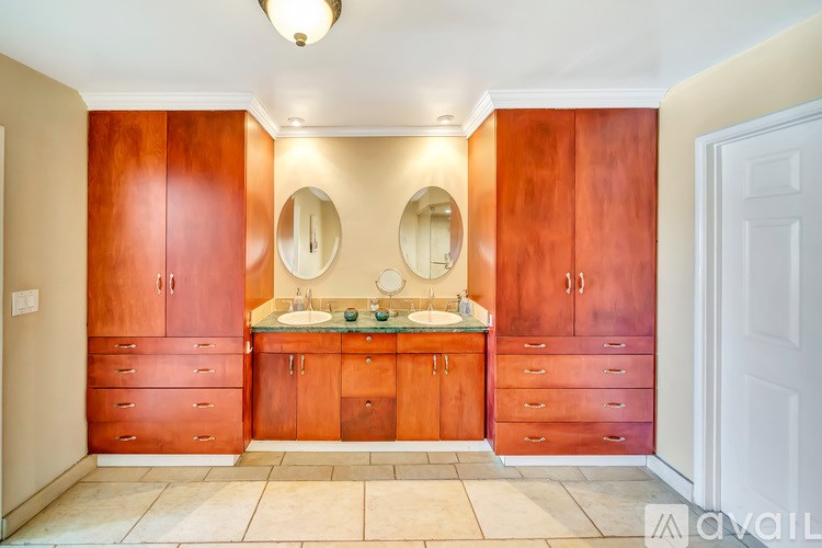 A bathroom with brown cabinets and a white door.