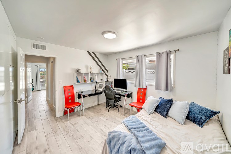 A bedroom with a bed, desk, and chairs.