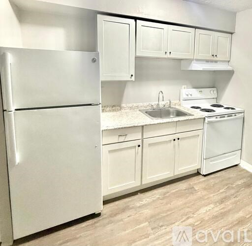 A white refrigerator is in a kitchen with white cabinets.