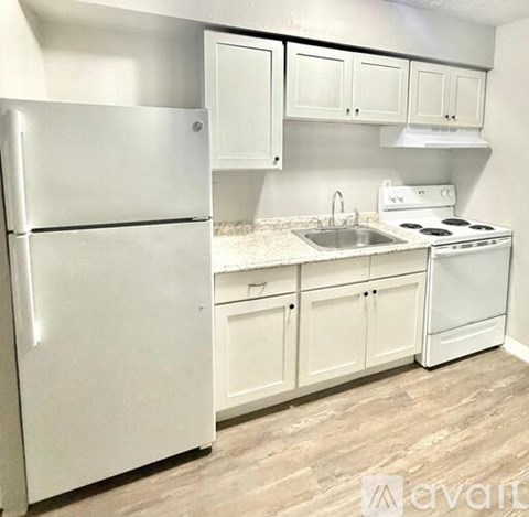 A white refrigerator is in a kitchen with white cabinets.