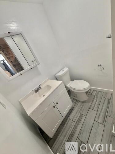 A bathroom with a toilet, sink, and mirror.