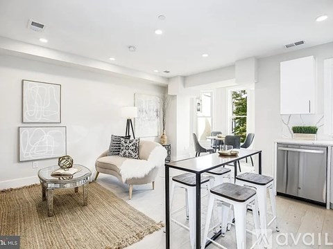 A modern living room with a white sofa, a glass coffee table, and a rug on the floor.