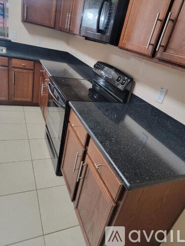 A kitchen with brown cabinets and a black countertop.