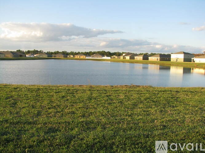 A body of water with a grassy shore and buildings in the distance.