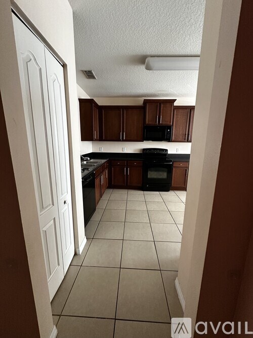 A kitchen with brown cabinets and black appliances.