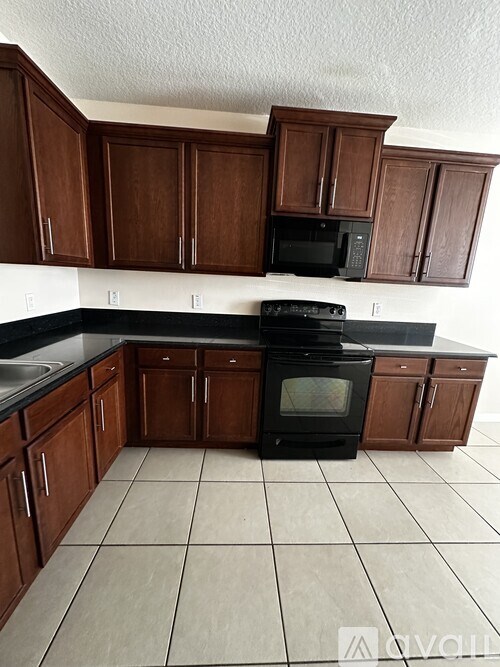 A black oven in a kitchen with brown cabinets.