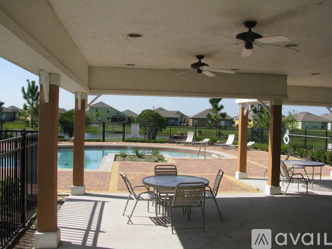A patio with a table and chairs overlooking a pool.