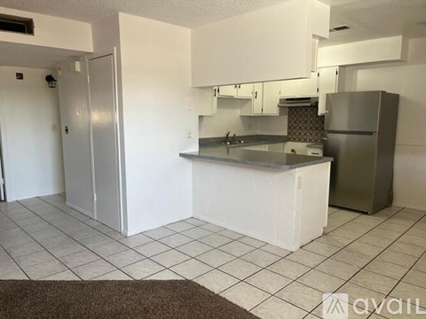 A kitchen with white cabinets and a white island with a refrigerator on the right.