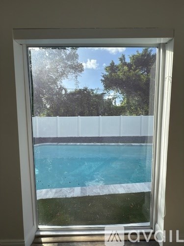 A window with a view of a pool and trees.