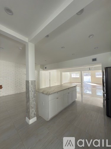 A spacious, well-lit kitchen with white cabinets and a central island.