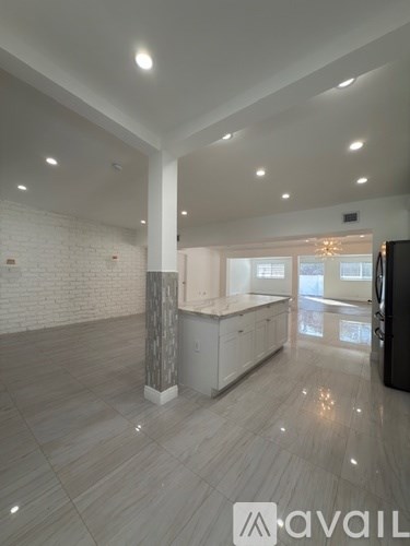 A spacious, well-lit kitchen area with a white brick wall and a central island.