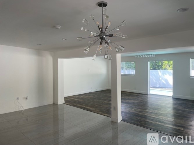 A spacious room with a chandelier and wooden flooring.