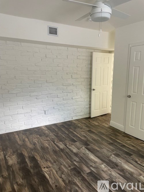 A room with a wooden floor and a white ceiling fan.
