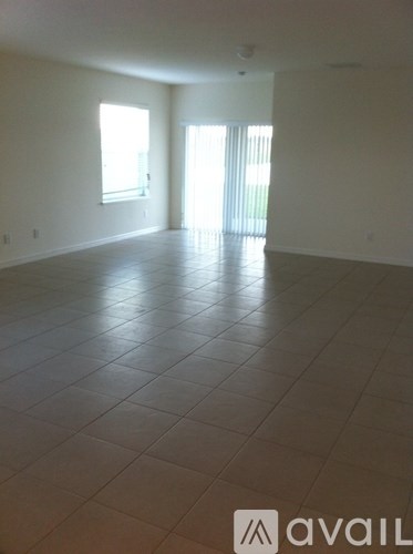 A spacious room with tile flooring and two windows.