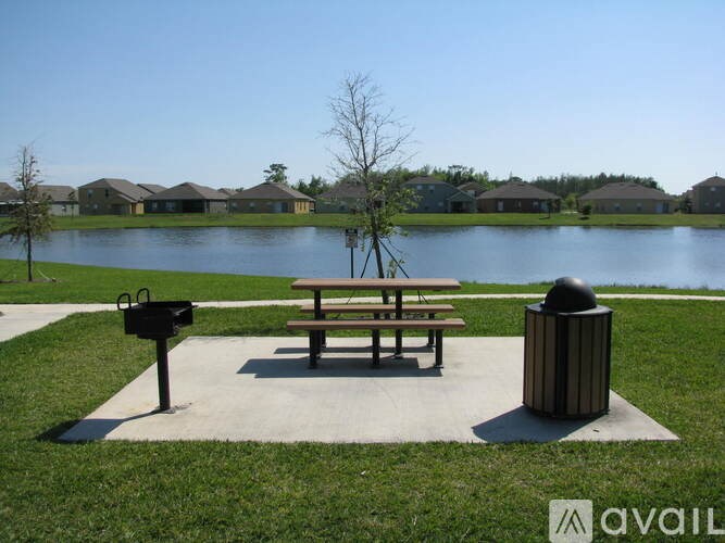 A park with a bench, a mailbox, and a trash can.
