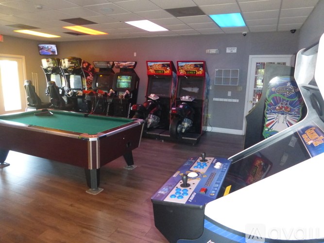 A room with a pool table, pinball machines, and a carnival game.