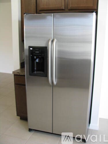 A stainless steel refrigerator with a black ice maker is in a kitchen.