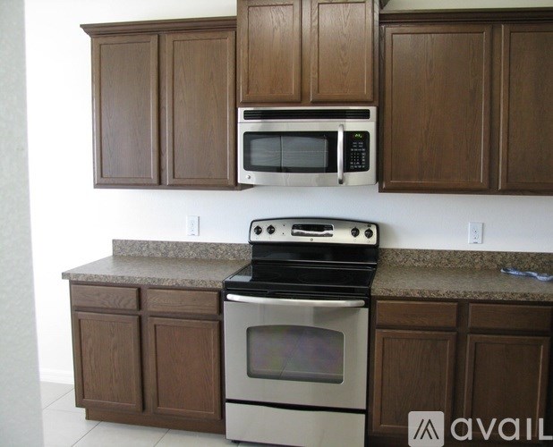 A kitchen with brown cabinets and a white microwave above a stove.