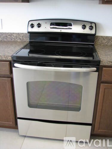 A black and white oven with a glass door is on top of a white oven with a wooden cabinet.