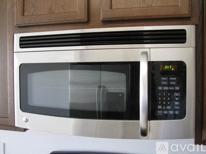 A silver microwave with a digital clock showing 21:11 is on a kitchen counter.