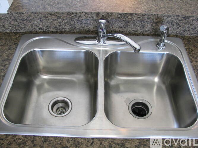 A double sink stainless steel kitchen sink with two faucets.
