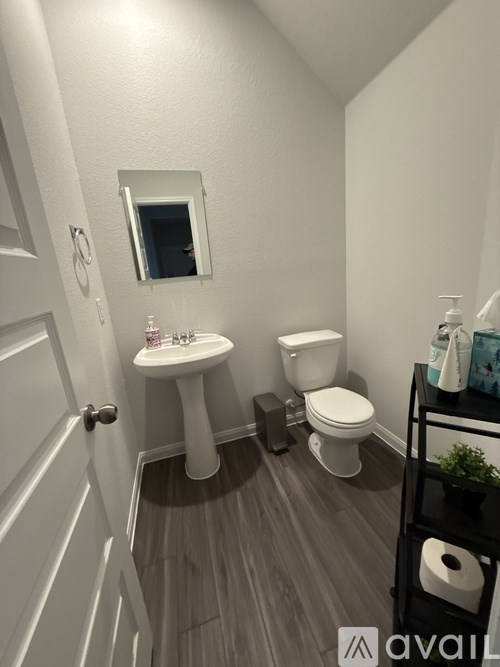 A bathroom with a toilet, sink, and mirror.
