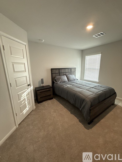 A bedroom with a bed, nightstand, and a door.