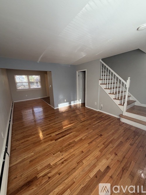 A room with wooden flooring and a staircase.