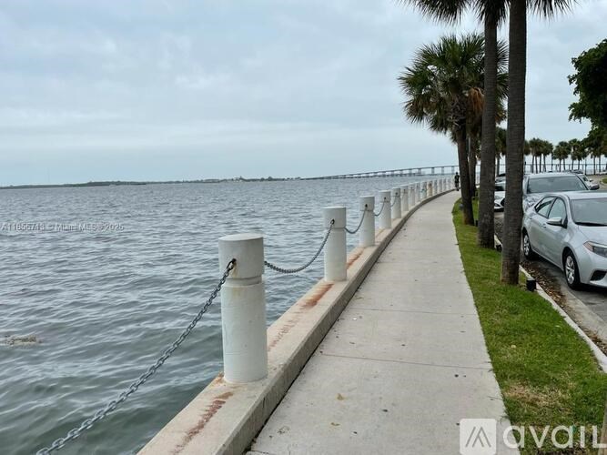 A silver car is parked on the side of a road next to a body of water.