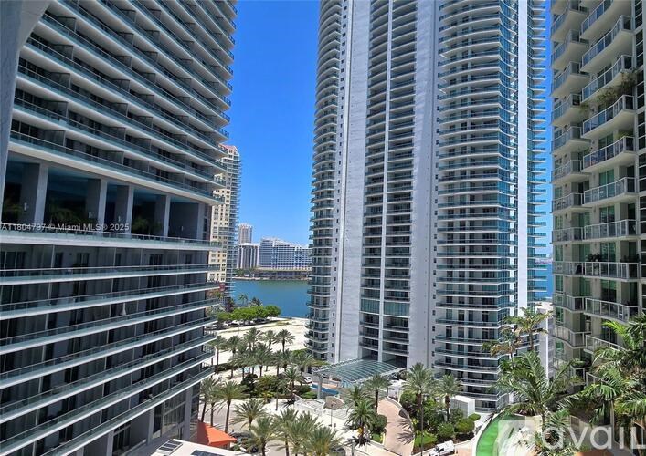 A view of a cityscape with tall buildings and a body of water in the distance.