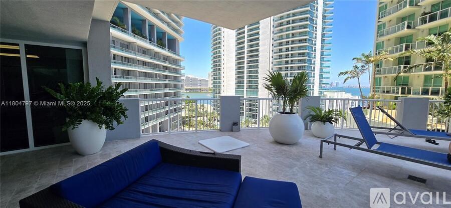 A balcony with a blue couch and a white table with a plant on it.