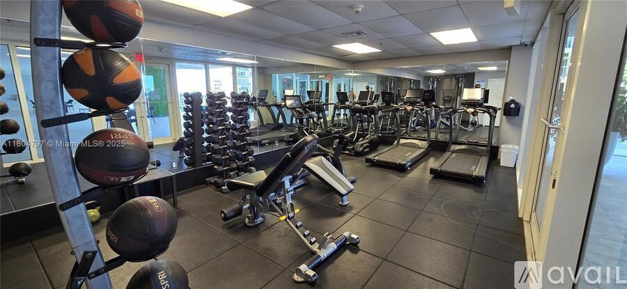 A gym with a variety of equipment including treadmills, weights, and exercise balls.