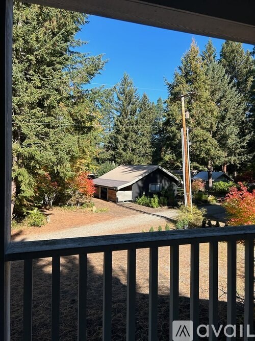 A house is seen through a window with trees in the background.
