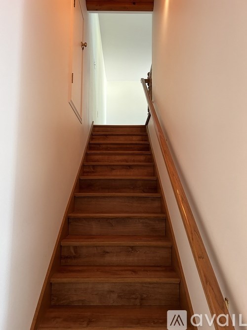 A wooden staircase with a white wall on the side.
