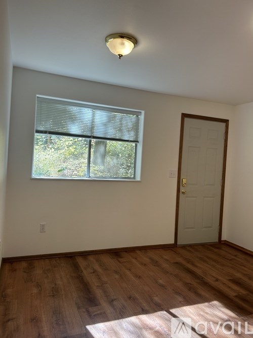 A room with a wooden floor and a window with blinds.