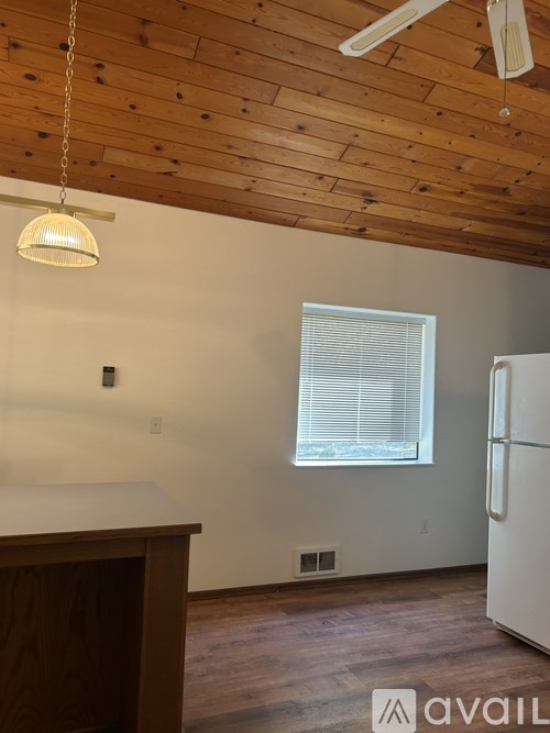 A kitchen with a white fridge and wooden ceiling.