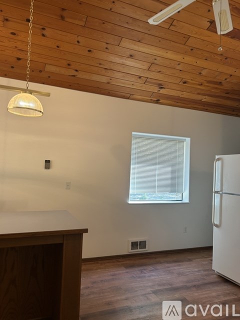A kitchen with a white fridge and wooden ceiling.