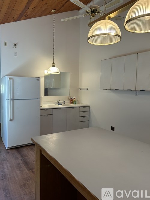 A kitchen with a white fridge and a wooden ceiling.