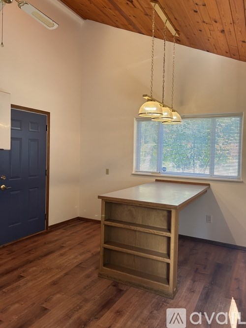 A room with a wooden floor and a cabinet with a window above it.